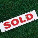 Sold sign sitting on green grass
